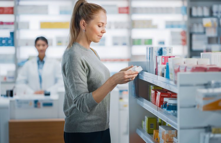 A woman at a pharmacy examining a box of medication